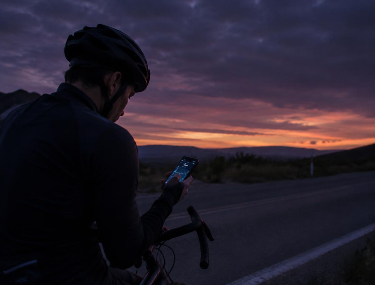A cyclist checking the Cadence app at dusk