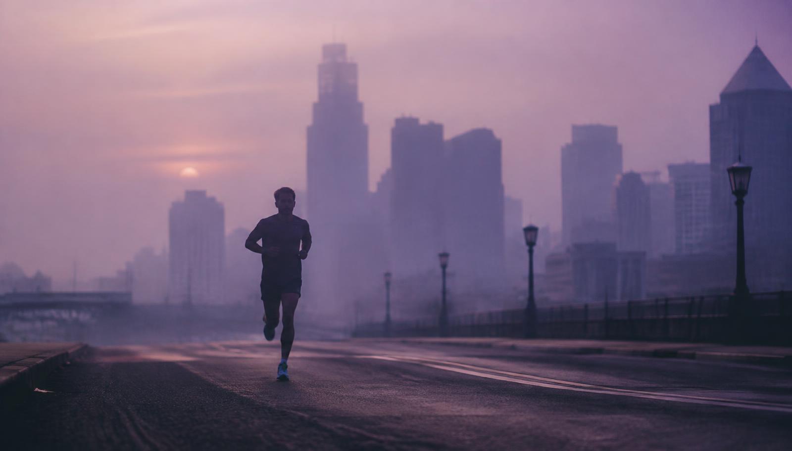 A runner crossing a quiet city at dawn